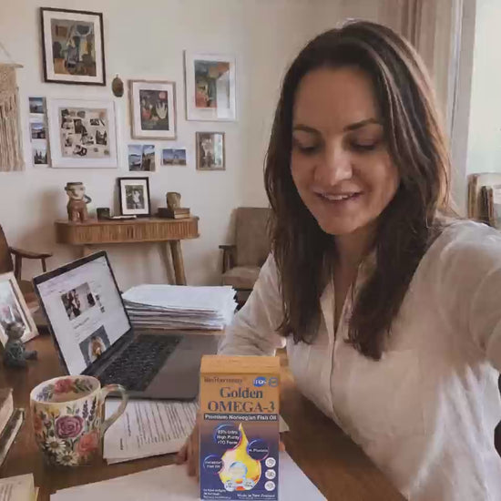 Customer review video thumbnail of a woman at a home desk showing BioHarmony Golden Omega-3 fish oil box next to a laptop (影片 / video)