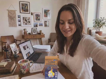 Customer review video thumbnail of a woman at a home desk showing BioHarmony Golden Omega-3 fish oil box next to a laptop (影片 / video)
